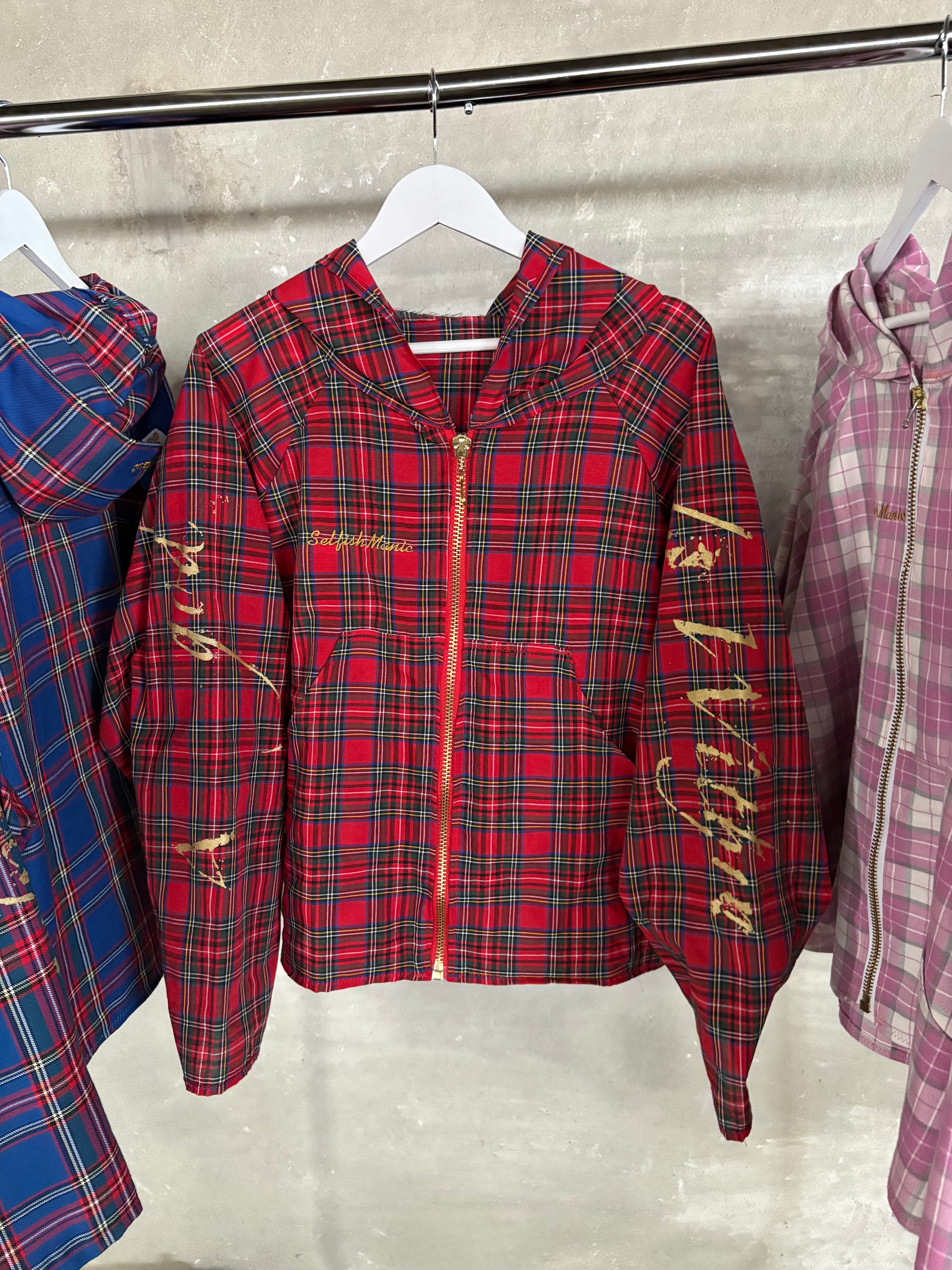 Red plaid jacket with gold text on a hanger against a neutral background
